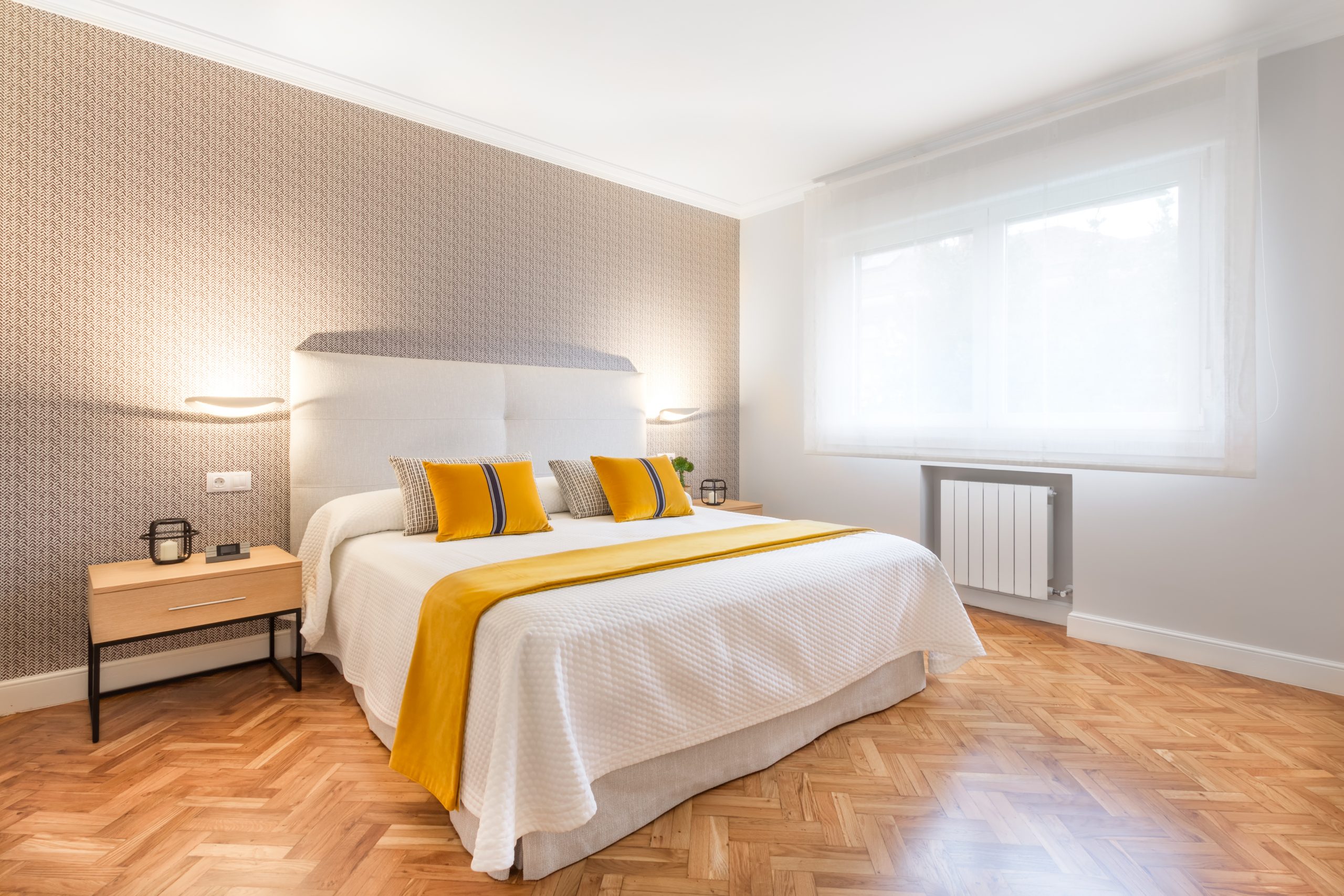 Dormitorio empapelado con cabecero de tela decorado por Tribeca Bilbao.
